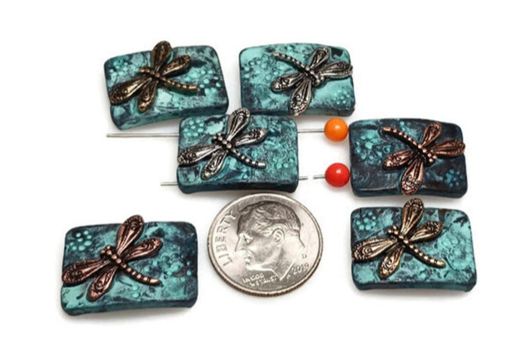 These dragonfly 2-hole metal slider beads with a patina background and gold or silver dragonfly accents bring a vibrant and textured charm to your jewelry designs.