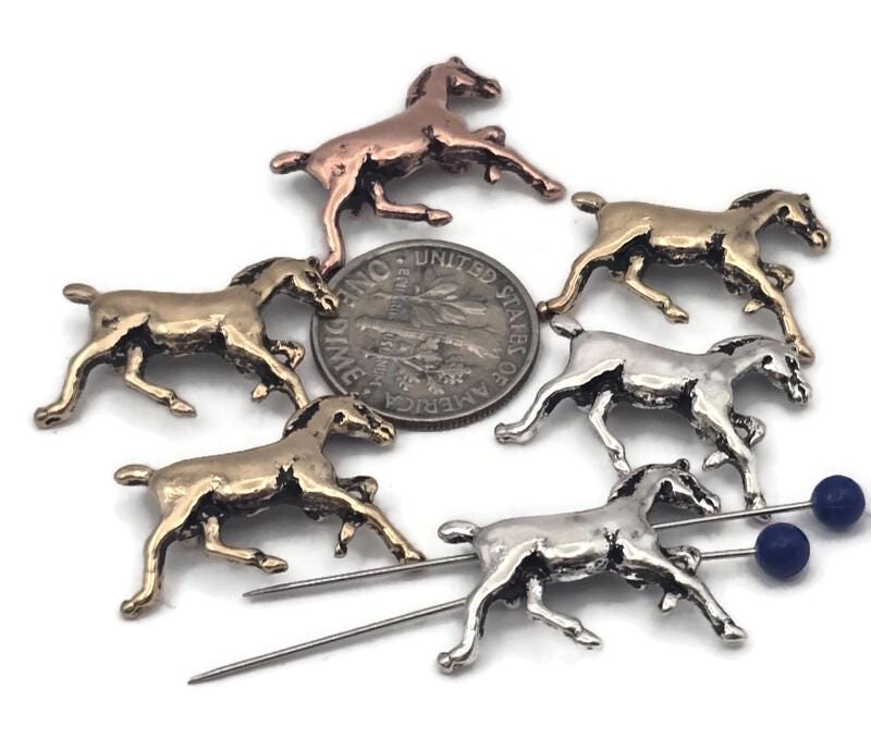 Galloping horse 2‑hole slider beads in antique silver, rustic copper, and aged brass. Detailed manes and legs create movement that pops in photos. Use as bracelet centerpiece, spacer bar, or pendant bar charm for cowgirl, rodeo, and western jewelry. Perfect for equestrian gifts, 4‑H fundraisers, and horse‑lover bracelets. Pair with turquoise howlite, jasper, or leather‑accented clasps.