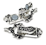 Decorative single-strand fold over magnetic clasp in bright silver finish featuring elegant black enamel scrollwork accents and ornamental detailing. Shown in both open and closed positions to demonstrate the hinged fold-over design and magnetic closure system. Each end includes a single attachment loop for connecting jewelry designs. Perfect for handmade bracelets, beading projects, artisan jewelry, magnetic bracelet closures, and custom jewelry making supplies.