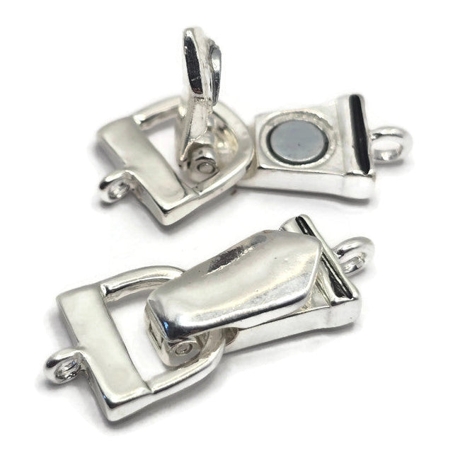 Bright silver fold over magnetic clasps displayed in both open and closed positions, showing the secure hinged design and magnetic closure system. These bracelet clasps feature attached loops for easy connection to jewelry designs and provide a polished professional finish. Ideal for handmade bracelets, jewelry making supplies, beading projects, magnetic bracelet closures, artisan jewelry, and custom bracelet designs that require easy-to-use secure findings.