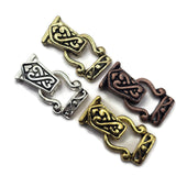 Four ornate Celtic knot metal fold over magnetic clasps pieces in gold, silver, and bronze finishes, arranged diagonally on a plain white background.