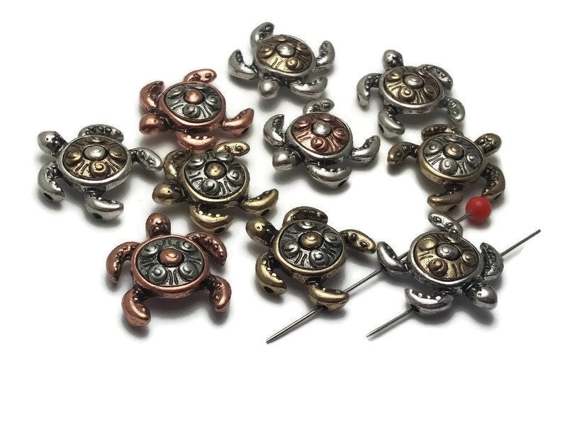 These mixed metal 2-hole slider beads in the shape of turtles are a unique and charming addition to any jewelry maker&#39;s collection, perfect for bracelets and necklaces.