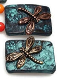 The patina background gives the beads an antique, vintage feel, while the gold or silver dragonflies provide an elegant and modern touch.