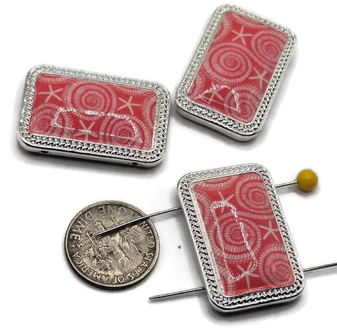 Bright silver 2 hole slider beads with glossy coral‑pink panels featuring a seashell and starfish pattern. Use these rectangular metal beads as focal sliders, spacers, or connector components in bracelets, chokers, and necklaces. Frame with seed beads as filler beads, add pearls or crystals for beach sparkle, or mix with sea‑glass colors for coastal palettes. Ideal beading components and findings for jewelry making, summer collections, beach weddings, and small‑batch wholesale.