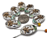 Celebrate summer style with these oval palm tree slider beads. Designed with a detailed golden palm tree, ocean wave accents, and abalone shimmer, these beads capture the beauty of the tropics. Their two-hole slider construction makes them easy to use in corded bracelets, layered necklaces, and boho anklets. Perfect for coastal jewelry collections, beach gift shops, and handmade vacation-inspired jewelry.