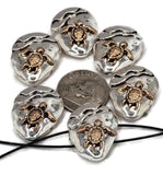 Round turtle slider beads with two holes, finished in silver with raised bronze turtles. Ideal for coastal jewelry making, nautical bracelets, focal pendants, or beach-themed handmade accessories. Perfect for DIY artisans and ocean bead collections.
