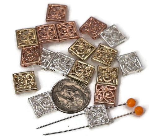 Square filigree 2 hole slider beads in mixed finishes of silver, gold, and copper. Each bead features a swirling floral scroll design, making them elegant focal beads for necklaces, bracelets, and pendants. Their two-hole construction ensures a flat, secure fit, perfect for boho, vintage, or modern handmade jewelry projects.