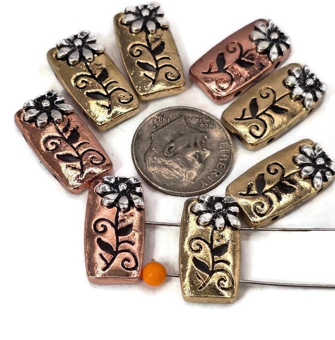 These rectangular 2 hole slider beads feature a raised white-silver daisy flower with embossed vines, set against shiny antique copper or rustic gold finishes. Each bead is crafted from durable alloy and flat-backed for stability. With their two-hole slider design, they sit securely in multi-strand creations, making them ideal for handmade bracelets, pendants, or chokers.