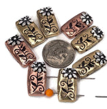These flower slider beads bring detailed floral beauty to your jewelry projects. Shaped in a rectangular form, each bead showcases an embossed flower and vine with raised silver accents against warm gold or copper toned backgrounds. The two-hole slider layout allows flat mounting in designs, ensuring stability for multi-strand jewelry. Excellent as focal beads or decorative spacers, they’re ideal for artisans making boho, garden, or vintage-inspired handmade bracelets and necklaces.
