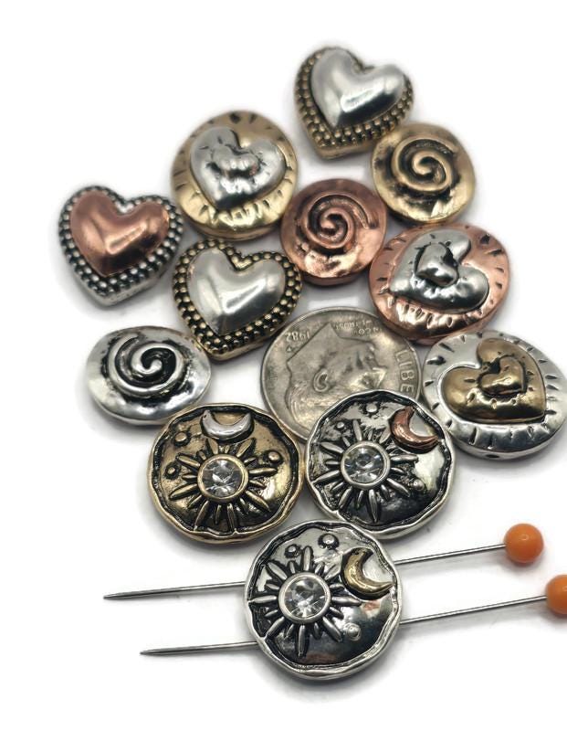 This collection of two-hole slider beads features hearts, spirals, and celestial sun & moon designs with rhinestones. Each bead has antique silver, bronze, or copper finishes that add rustic elegance to boho and artisan jewelry. Perfect for bracelets, necklaces, and anklets, these versatile beads capture meaningful symbols and timeless style for your handmade jewelry projects.