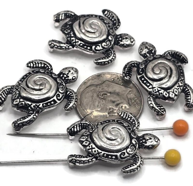 These antique silver sea turtle 2-hole slider beads are perfect for ocean and nautical jewelry designs. Each bead features a detailed turtle with a spiral shell, tribal-style patterns, and an aged silver finish for a rustic boho look. The 2-hole design makes them ideal for leather cord bracelets, chokers, and statement necklaces. Great for coastal jewelry, beach-inspired gifts, bohemian designs, or sea turtle lovers, these beads are symbolic of wisdom, longevity, and protection.