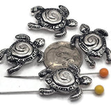 These antique silver sea turtle 2-hole slider beads are perfect for ocean and nautical jewelry designs. Each bead features a detailed turtle with a spiral shell, tribal-style patterns, and an aged silver finish for a rustic boho look. The 2-hole design makes them ideal for leather cord bracelets, chokers, and statement necklaces. Great for coastal jewelry, beach-inspired gifts, bohemian designs, or sea turtle lovers, these beads are symbolic of wisdom, longevity, and protection.