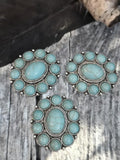 These two-hole turquoise slider beads are bold statement components for artisan designs. Each bead features a large oval faux turquoise cabochon surrounded by smaller matching stones, set within a silver rope-style frame. With dual holes for alignment, they make excellent focal connectors for multi-strand bracelets, necklaces, or chokers. Their vibrant blue tones and symbolic design enhance handmade jewelry projects.