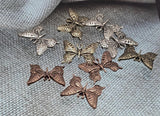 Create uplifting jewelry with these mixed‑finish butterfly slider beads. Each bead highlights ornate wing cutouts in antique silver, copper, or brass plating. With two holes for stability, they work beautifully as connectors and focal components in multi‑strand bracelets, necklaces, and choker designs. Their symbolic nature adds meaning, while their decorative detail makes them a versatile artisan jewelry supply.