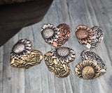 Celebrate sunflowers and love with these heart-shaped 2‑hole slider beads. Embossed with sunflowers and floral vine designs, they come in antique silver, brass, and copper finishes that won’t tarnish or wear off. Perfect for use as focal pendants or centerpiece beads in artisan necklaces and bracelets, they bring rustic detail and heartfelt symbolism to handmade artisan jewelry projects.