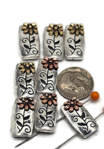 These rectangular 2 hole slider beads feature a raised daisy flower in copper or gold against an antique silver base with engraved vines. Their two-hole slider layout ensures the beads stay flat and balanced, making them perfect for bracelets, necklaces, or chokers. With rustic charm and floral beauty, they work well as focal beads or decorative spacers in handmade, bohemian, or garden-inspired jewelry. Durable metal alloy construction makes them a must-have DIY jewelry finding.