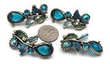 Opulent teal glass focal sliders bring instant luxury to your designs. Beaded bezels, botanical branches, and enamel leaves surround sparkling rhinestones on antique brass. The 2‑hole construction keeps the component steady on bracelet bands or pendant bars. Ideal for statement necklaces, corsage bracelets, and boutique jewelry with vintage charm.