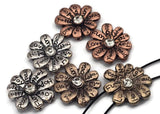 Craft uplifting accessories with these affirmation flower sliders in silver, copper, and gold tones. Each petal is inscribed—Love, Hope, Joy, Faith—around a faceted crystal center. The two-hole slider construction ensures secure, flat placement in bracelets, chokers, and layered necklaces. Great as focal beads or bold spacers in bohemian and wellness-inspired handmade jewelry collections.