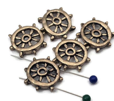 Steer your designs with these ship’s wheel 2 hole slider beads. Each antique-brass wheel is cast in durable, non‑tarnish metal with open spokes and a bold rim. Dual holes keep the focal flat and secure on leather, cord, or chain—perfect for bracelets, chokers, pendants, earrings, and rings. A classic nautical motif for coastal gifts, beach jewelry, and sailor-inspired collections. Package includes 5 matching sliders.