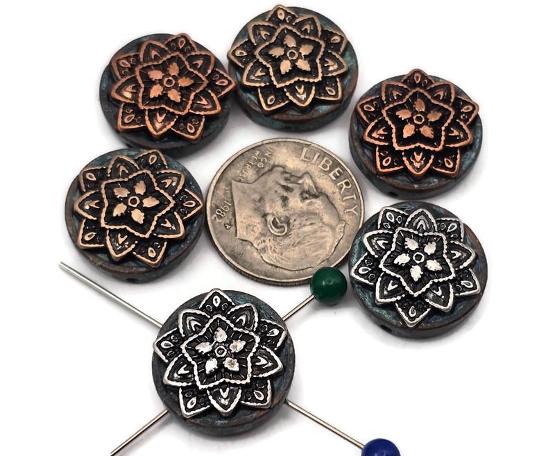 Add boho flair with these mandala 2 hole slider beads. Raised floral medallions in warm copper and antique silver sit atop teal patina rounds. Dual holes keep the focal flat and secure on leather, cord, or chain—perfect for bracelets, chokers, pendants, earrings, and rings. Durable, non‑tarnish mixed‑metal finish. Package includes 6 matching sliders as shown.