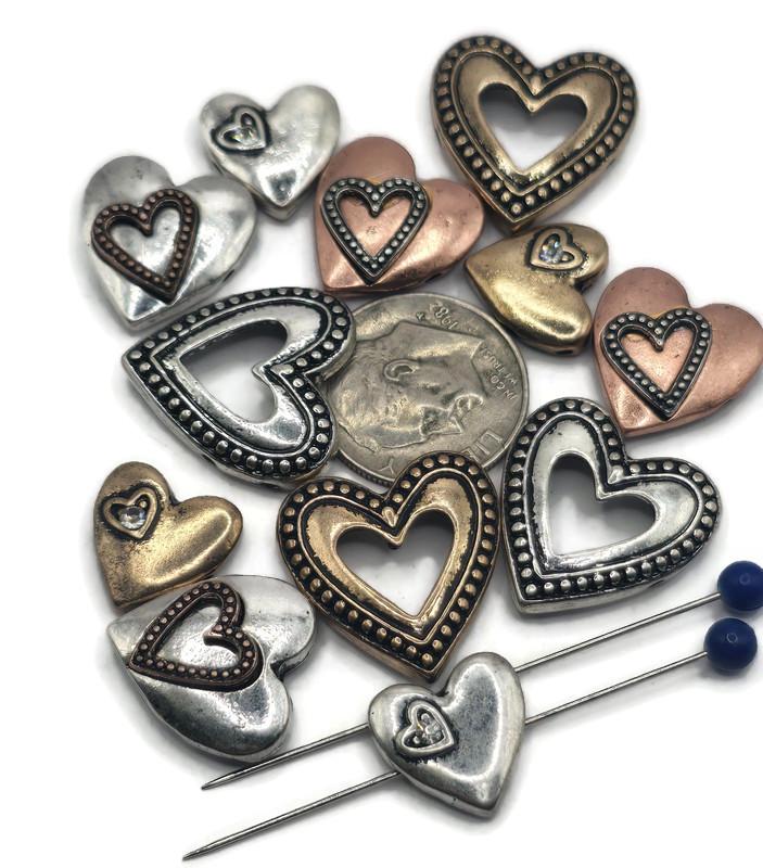 These rustic 2-hole heart slider beads are ideal for boho and romantic jewelry. Available in antique silver, bronze, and copper finishes, the designs include solid puffed, open, and layered double hearts. With a dual-hole slider construction, they stay secure and flat in bracelets, chokers, and necklaces. Perfect for Valentine’s jewelry, symbolic handmade gifts, and artisan accessories celebrating love.