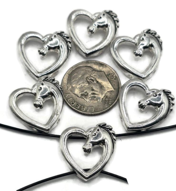 These horse slider beads are perfect for equestrian jewelry lovers. Each bead features a beautifully detailed horse head within a heart-shaped frame, finished in rustic antique silver. With dual-hole slider construction, they sit flat and secure in bracelets, chokers, and necklaces. Great for boho artisan jewelry, Western-inspired accessories, or handmade gifts celebrating horses, love, and country living.