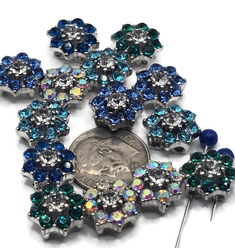These rhinestone flower slider beads bring stunning sparkle to handmade jewelry. Designed in vibrant shades of aqua, blue, green, and iridescent AB crystal, each bead features shimmering petals and a clear rhinestone centerpiece. Their silver-tone base and dual-hole slider design ensure secure, balanced strands for chokers, bracelets, and artisan necklaces. Perfect for dazzling festival jewelry, statement boho pieces, or elegant handmade gifts.