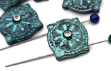 Unique beads for makers who want impact fast. These square pillow sliders showcase a teal verdigris wash over sculpted details, finished with a bright crystal. Two parallel holes keep designs aligned for a professional look. Excellent focal beads for artisan drops, photo‑friendly and conversion‑ready. Durable metal beads with character—perfect for statement cuffs, charm chokers, and pendant centers.