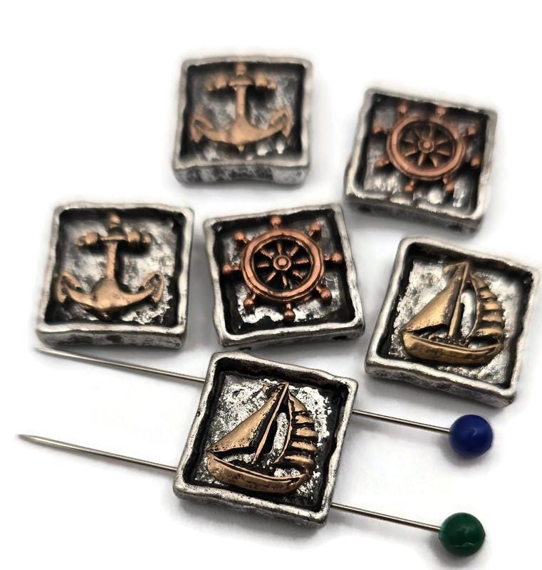 Bring seaside charm to your collection with these nautical sliders. The sculpted sailboat, wheel, and anchor sit inside rustic square frames with hand‑worn edges. Mixed silver and bronze tones highlight the relief work and create a classic maritime feel. Excellent as focal beads in bracelets or as pendant accents on necklaces. Subtle finish variations give every package an artisan touch.
