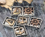 Nautical 2 hole slider beads with raised motifs—sailboat, ship wheel, and anchor—framed in softly squared bezels. Antiqued silver grounds warm bronze details for rich contrast. Each bead has intentional texturing that photographs beautifully. Versatile focal beads for bracelet designs and pendants on necklaces. Unique beads and premium metal findings with a sturdy, dimensional look that adds coastal character to handmade pieces.
