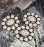 These ornate oval slider beads combine beauty and practicality for jewelry makers. The central white faux howlite cabochon is bordered by small matching cabochons in a raised, antique silver frame. Two side holes create stability, perfect for aligning multi-strand bracelets, chokers, and necklaces. Ideal focal connectors for artisan jewelry, they add elegance, symbolism, and handcrafted character to your creations.
