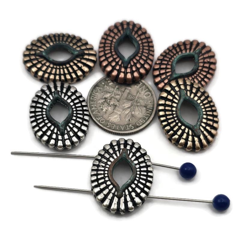 Sunburst oval 2 hole slider beads with a marquise‑shaped opening and teal verdigris accent. Mixed metals—antique silver, rustic copper, and aged brass—highlight the raised rib texture. Use as bracelet focal, spacer bar, or pendant bar charm in double‑strand designs. These coin connectors sit flat and photograph beautifully, ideal for boho, tribal, and southwestern jewelry.