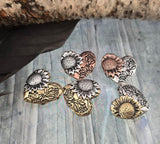 Add elegance and meaning to your jewelry designs with sunflower heart slider beads. Each bead features raised sunflower and floral detailing, crafted in antique silver, brass, and copper finishes that resist tarnishing. With two alignment holes, they are ideal for necklace pendants or bracelet focals. Perfect artisan supplies for rustic, boho, or nature-inspired handmade jewelry collections with floral charm.