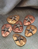 Bring seaside inspiration to your jewelry designs with these artisan starfish slider beads. Each bead highlights a raised detailed silver starfish on a smooth brass or copper‑finished stone base. With two‑hole construction, they align perfectly in bracelets or pendant necklaces. Ideal artisan supplies for nautical, boho, or summer jewelry collections that celebrate the ocean and coastal living.