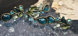 These vine and leaf 2‑hole slider beads shimmer with faceted teal stones and aurora accents. Antique brass plating and enamel leaves deliver romantic Art Nouveau style. Dual holes provide alignment for cuff bracelets, chokers, and collar necklaces. A beautiful choice for boho glam, cottagecore, and garden‑themed handmade jewelry.