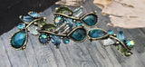 Teal rhinestone vine sliders deliver instant focal drama. Antique brass settings, dotted bezels, and enamel leaves create layered dimension. The 2‑hole orientation prevents twisting in bracelets and pendant bars. Ideal for romantic, vintage, or Art Deco‑inspired jewelry that blends sparkle with organic botanical lines.