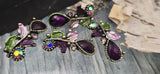 Create statement jewelry with purple resin teardrops framed by beaded bezels and sparkling crystal accents. Enamel leaves in lilac and moss wrap around antique brass or antique gold vines. The 2‑hole slider construction keeps pieces centered in bracelets and necklace bars. Ideal for bridal party accessories, evening designs, and vintage‑inspired collections with rich jewel tones.