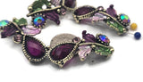 Purple resin teardrops and sparkling crystals shimmer across antique metal vines. Enamel leaves add soft garden hues. The 2‑hole slider design provides structure and a flat fit, perfect for cuffs, chokers, and pendant connectors. Use in evening, wedding, or boutique jewelry needing rich jewel tones and artisan detail.