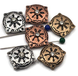 Statement-ready sun medallion 2 hole slider beads in antique silver, copper, and brass tones. Each bead showcases detailed engraving and a sparkling center crystal for light-catching drama. Unique beads and dependable metal findings that elevate handcrafted pieces with a heritage aesthetic. Purposefully aged finishes emphasize the pattern and add warmth, making these metal beads perfect for curated artisan collections and gifts.