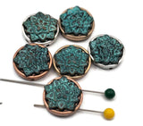 Round lotus flower 2 hole slider beads with a vibrant turquoise patina and mixed-metal settings. Each bead features a raised floral motif in verdigris, framed by antique silver, copper, or brass tones. These unique beads make stunning focal beads for bracelet designs and pendants on necklaces. The dimensional texture and rich color variations add artisan character to any handmade jewelry collection.