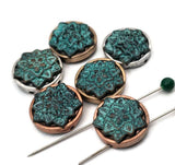 Artisan lotus flower 2 hole slider beads with a striking verdigris finish. Each round bead showcases a raised floral design, framed by an antiqued metal setting. The intentional patina and mixed-metal tones create rich depth that photographs beautifully. Ideal focal beads for bracelet builds and necklace pendants, adding a touch of nature-inspired elegance to handmade pieces.
