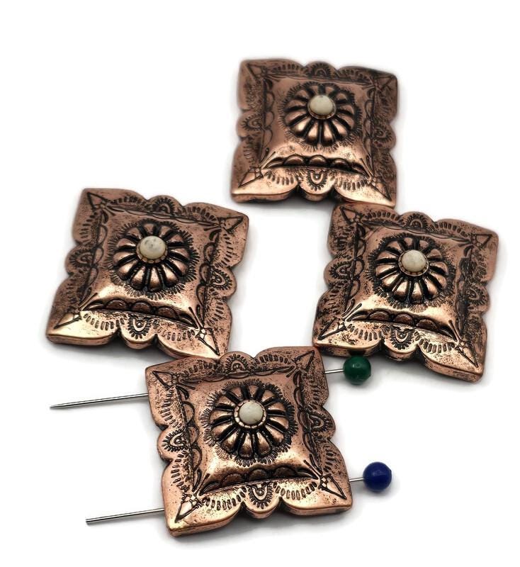 Western concho beads, 2 hole slider style, in warm antique copper. Square scalloped concho with engraved scrollwork and a domed rosette center accented by a cream cabochon. Unique focal beads for bracelet designs and simple pendant centers on necklaces. Keywords: concho bead, copper concho slider, western jewelry supplies, boho southwestern bead, floral concho focal.