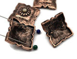 Southwestern concho 2 hole beads featuring ornate engraving, rope borders, and a central flower. The antique copper finish gives a rustic, ranch-inspired look. Use as focal beads for bracelet stacks or as pendant accents. Keywords: western concho charm, copper concho focal, rodeo jewelry supplies, boho ranch bead, metal slider.