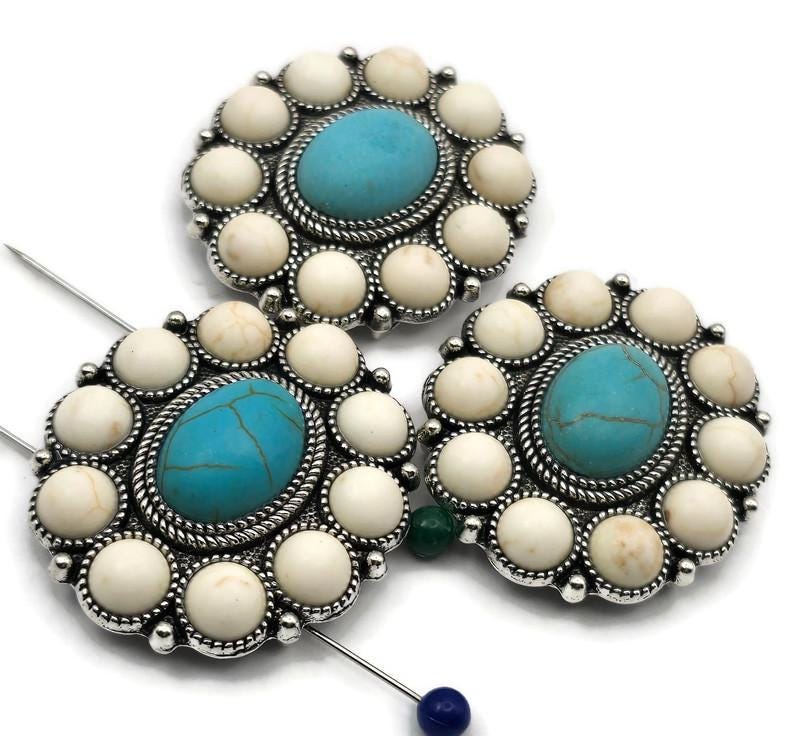 Large concho 2 hole slider beads with turquoise center and ivory cabochon border in antique silver. Round rosette focal beads for bracelets and necklaces. Small parallel holes fit fine beading wire, FireLine, or micro cord (not leather/chain). Great statement components for boho, Southwestern, festival, and cowgirl‑chic jewelry. Bulk wholesale metal supplies; unique spacer/filler DIY parts. Set of 3.