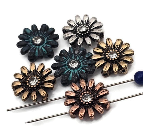 Daisy flower 2‑hole slider beads with sparkly rhinestone centers. Mixed finishes: antique silver, warm copper, golden brass, and patina teal. True double‑strand slide design; two small parallel holes fit fine beading wire, FireLine, or micro cord (not leather/chain). Perfect focal beads for crafting bracelets, chokers, anklets, and spring jewelry. Floral beads for beading projects, DIY supplies, components, findings.