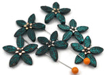 Statement florals made simple: teal patina two hole slider beads with etched leaves and metallic centers. Build fast bracelets by centering one flower and tapering seed beads toward the clasp, or make a pendant by attaching chain on both sides. Mix with copper and silver for mixed‑metal styling. Essential metal beads, spacer/connector components, and beading supplies for DIY makers and boutique wholesale.
