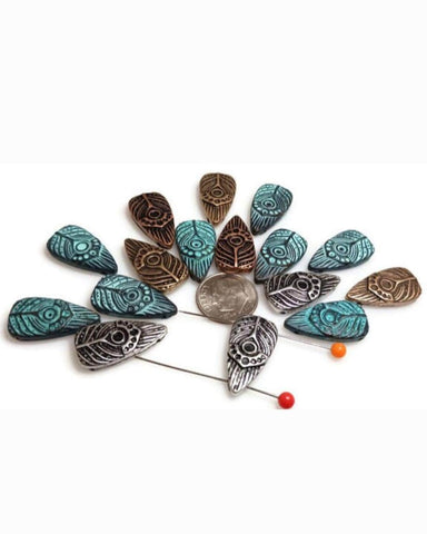 Boho teardrop 2‑hole slider beads with tribal eye patterns. Mixed finishes—antique silver, rustic copper, aged brass, and teal verdigris—show crisp engraved lines. Use as bracelet centerpiece, spacer bar, or pendant bar charm. These slim drops sit flat and create striking double‑strand bracelets, layered chokers, and anklets. Pair with turquoise howlite, jasper, seed beads, or crystal for festival‑ready jewelry.