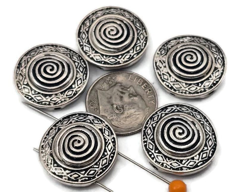 Antique silver spiral 2 hole slider beads with a raised swirl center and geometric border. These round metal beads make easy focal sliders, spacers, or connector components for bracelets, chokers, and necklaces. Frame with seed beads as filler beads; add crystals, gemstones, or heishi for texture. Timeless beading components and findings for boho, tribal, and Southwestern jewelry. Lead and nickel compliant jewelry making supplies for DIY kits and small‑batch wholesale.