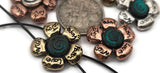 These mixed‑metal flower 2‑hole slider beads feature engraved uplifting words and spiral centers washed in teal verdigris. Used as bracelet focals, double‑strand connectors, or pendant bar spacers, they bring unique character and intention to handmade designs. Their balanced shape and dimensional petals make them ideal for casual bohemian, spiritual, and affirmation jewelry.