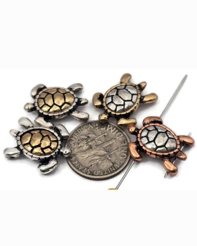Sea turtle 2‑hole slider beads in mixed metallic finishes—antique silver, brass, and copper—bring coastal charm to jewelry designs. Each bead features a smooth, raised shell with defined flippers and balanced dual holes for clean double‑strand alignment. Perfect for beach‑themed bracelets, chokers, or boho anklets celebrating ocean life and natural beauty.